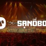 picture of the Sandbox metaverse logo and Warner Music logos side by side superimposed over a convert crowd